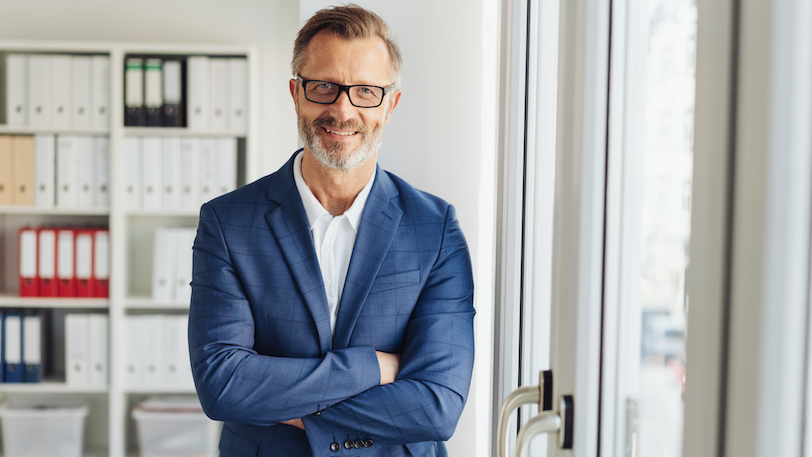 Middle-aged man standing in business suit smiling