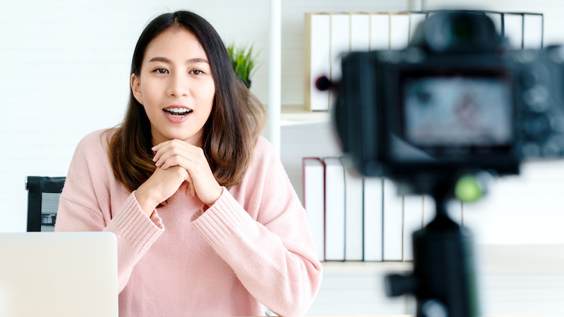 Young woman filming herself on camera